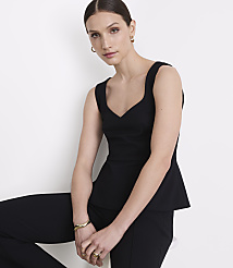 A woman in a black peplum top and pants poses against a plain white background. carousel Product Image 2