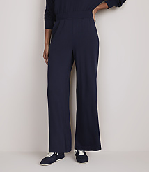 A person stands in navy blue wide-leg pants and sneakers against a plain, light-colored background. carousel Product Image 2