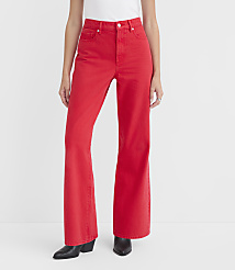 A person stands in the foreground wearing bright red flared jeans and black boots against a plain white background. carousel Product Image 1