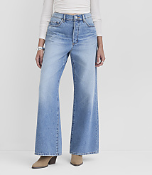 A person models light-wash wide-leg jeans and tan heeled boots against a plain white background. carousel Product Image 1