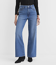 A person wearing high-waisted, wide-leg blue jeans and black boots stands against a plain white background. carousel Product Image 1