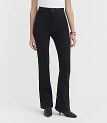 A person stands in black flare jeans and black heels against a plain white background. carousel Product Image 1
