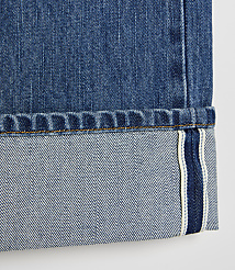 A close-up of cuffed blue denim jeans with a white background. carousel Product Image 5