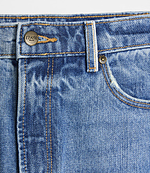 A close-up of blue denim jeans with a metal button and pocket in the foreground, set against a plain white background. carousel Product Image 4