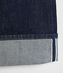 A close-up of dark indigo denim jeans with a cuffed hem showing the lighter interior fabric and selvedge edge against a plain white background. carousel Product Image 4