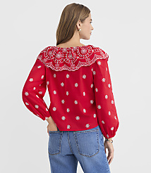 A woman in a red embroidered blouse and blue jeans stands against a plain white background. carousel Product Image 3