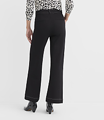A person wearing black flared pants with white stitching and black heeled boots stands against a plain white background. carousel Product Image 3