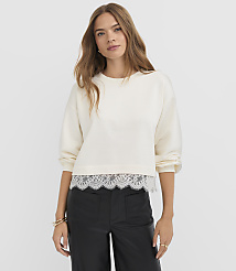A young woman in a cream sweatshirt with a lace hem stands against a plain white background. carousel Product Image 1