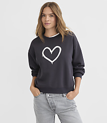 A young woman in a dark sweatshirt with a white heart graphic stands against a plain white background. carousel Product Image 2