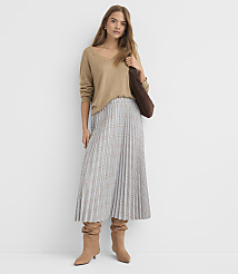 A woman in a tan sweater and plaid skirt stands against a plain white background, holding a brown bag. carousel Product Image 1