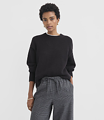 A woman in a black sweater and plaid pants stands against a plain white background. carousel Product Image 1
