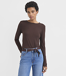 A woman in a brown long-sleeved shirt and blue jeans stands against a plain white background. carousel Product Image 1