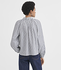 A woman wearing a black and white striped blouse and dark jeans stands against a plain white background. carousel Product Image 3