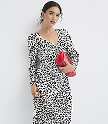 A woman in a black and white spotted dress holds a red clutch against a plain white background. carousel Product Image 1