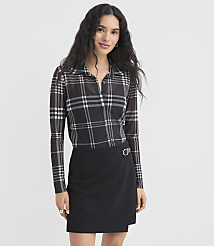 A woman with long dark hair stands in the foreground wearing a sheer plaid button-up shirt and a black wrap skirt against a plain white background. carousel Product Image 1