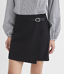 A woman in a black wrap skirt with a buckle detail stands against a white background. carousel Product Image 2