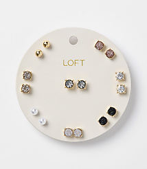 A circular white card displays a collection of assorted stud earrings, including pearls, gold balls, and various gem-encrusted designs, against a plain white background. carousel Product Image 1