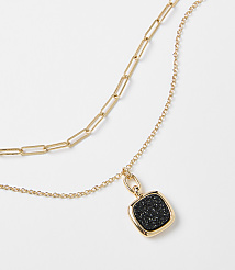 A layered gold necklace with a square black pendant hangs against a plain white background. carousel Product Image 2