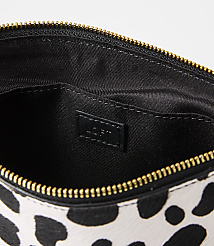 A black and white spotted clutch with a gold zipper is open to reveal its black interior, which has a "LOFT" logo tag. carousel Product Image 2