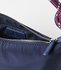 A close-up of a navy blue handbag with a braided strap is set against a plain white background. carousel Product Image 2
