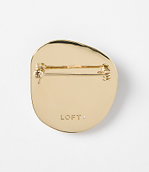 A gold-toned, irregularly shaped brooch with a pin backing is centered against a plain white background. carousel Product Image 2