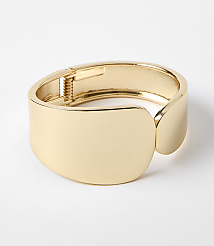 A polished gold cuff bracelet with a hinge closure rests on a plain white background. carousel Product Image 1