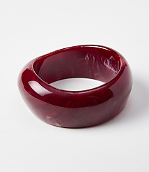 A glossy, deep red, abstractly shaped bangle with swirling white inclusions rests on a plain white background. carousel Product Image 1