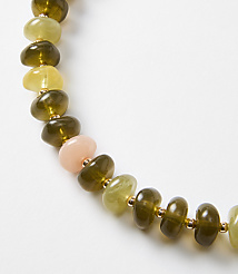 A strand of olive green, pale yellow, and pink beads with gold spacers curves across a white background. carousel Product Image 2