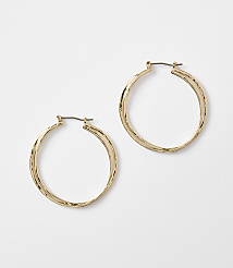 Two textured gold hoop earrings rest on a plain white background. carousel Product Image 1