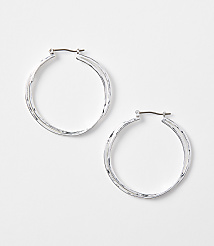 Two silver hoop earrings with textured surfaces rest on a plain white background. carousel Product Image 1