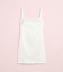 A white slip dress with thin straps is laid flat against a soft pink background. carousel Product Image 2