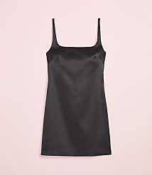 A black satin slip dress with thin straps is centered against a soft pink background. carousel Product Image 4