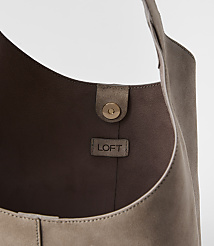A taupe suede hobo bag with a gold snap closure and a LOFT logo tag is shown against a plain white background. carousel Product Image 2