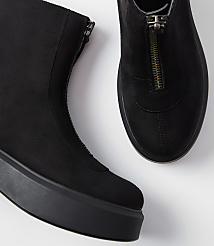 A pair of black suede ankle boots with front zippers rests on a white surface. carousel Product Image 2