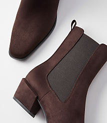 A pair of brown suede Chelsea boots with block heels are arranged on a white background, with one boot in the foreground and the other partially visible in the background. carousel Product Image 2
