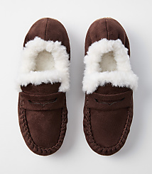 A pair of brown suede moccasin slippers with white fluffy lining are displayed against a plain white background. carousel Product Image 3