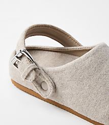 A close-up of a beige felt clog with a silver buckle and strap is set against a plain white background. carousel Product Image 2