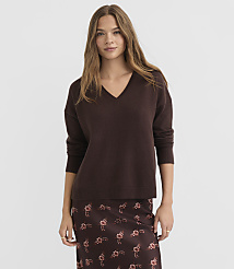 A woman in a brown v-neck sweater and floral skirt stands against a plain gray background. carousel Product Image 1