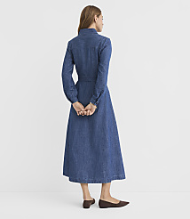 A woman in a denim dress stands with her hands clasped behind her back against a plain white background. carousel Product Image 3