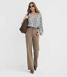 A woman in a floral blouse and wide-leg brown pants stands against a plain white background, carrying a brown tote bag. carousel Product Image 2
