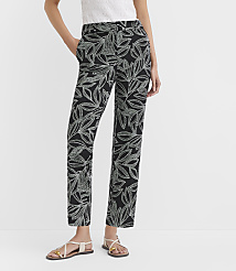 A person models black pants with a white leaf pattern, standing against a plain white background. carousel Product Image 2