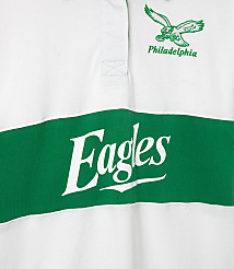 A white rugby shirt with a green stripe across the chest displays "Eagles" in large white lettering, while a green eagle logo and "Philadelphia" are embroidered on the upper right chest. carousel Product Image 3