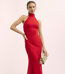 A woman in a red halter gown poses with a gold clutch against a soft pink background. carousel Product Image 1