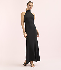 A woman in a black halter neck gown stands against a soft pink background. carousel Product Image 1