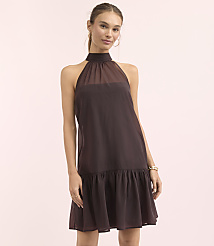 A woman in a dark brown halter dress stands against a soft pink background. carousel Product Image 1