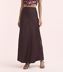 A woman in a long, dark purple skirt and a sequined top stands against a soft pink background. carousel Product Image 2