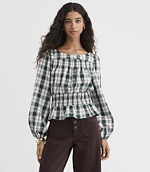 A woman in a green and white plaid smocked blouse and brown pants stands against a plain gray background. carousel Product Image 2