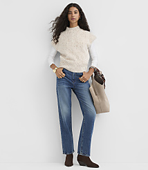 A woman in a cream speckled sweater vest and blue jeans stands against a plain white background, holding a tan tote bag. carousel Product Image 2