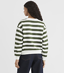 A woman in a green and white striped sweater and dark jeans stands against a plain white background. carousel Product Image 3