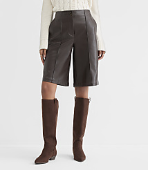 A person stands in brown leather culottes and knee-high brown boots against a plain white background. carousel Product Image 2